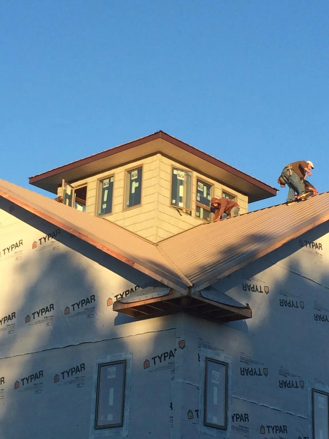 Roofers working around a rooftop cupola on a new metal roof at sunset — Roof Waterproofing in Copalis Beach by Roofing Brothers